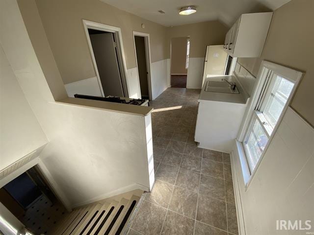 kitchen featuring refrigerator, sink, white cabinets, dark tile patterned floors, and kitchen peninsula