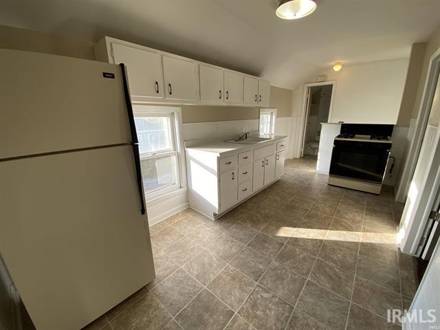 kitchen with white cabinetry, range with gas cooktop, lofted ceiling, and white refrigerator