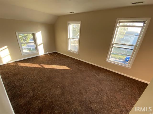 carpeted spare room featuring lofted ceiling