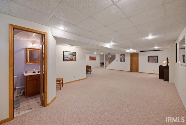 basement featuring a paneled ceiling and light carpet