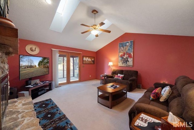 carpeted living room featuring french doors, ceiling fan, and vaulted ceiling with skylight