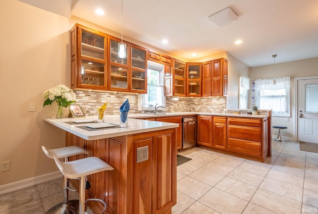 kitchen featuring backsplash, decorative light fixtures, kitchen peninsula, and a breakfast bar