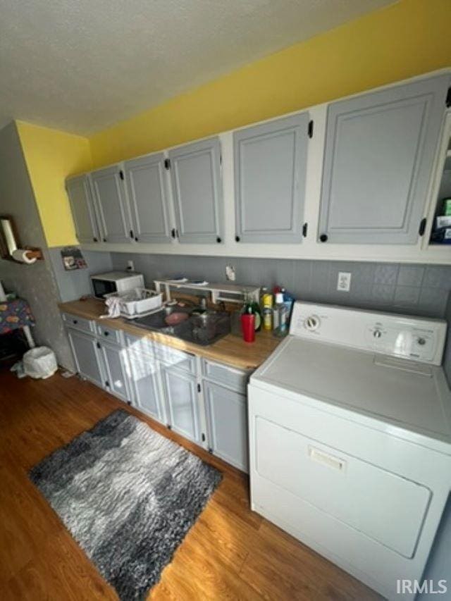 laundry room with washer / clothes dryer, sink, a textured ceiling, and light hardwood / wood-style flooring