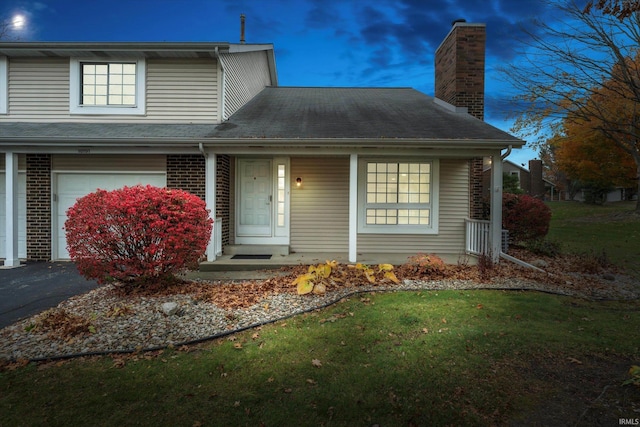 front facade with a garage, a porch, and a lawn