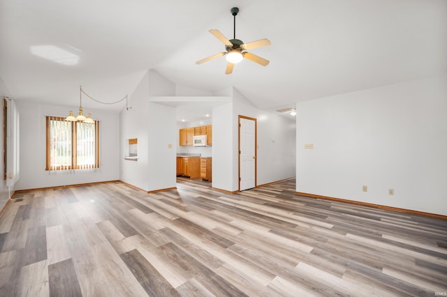 unfurnished living room with ceiling fan with notable chandelier, high vaulted ceiling, and light hardwood / wood-style floors