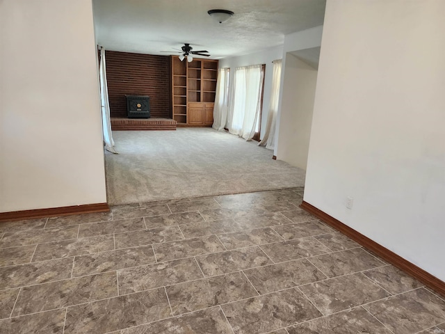 unfurnished living room with built in features, ceiling fan, and dark colored carpet