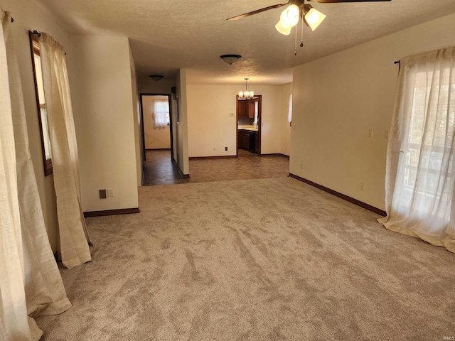 carpeted empty room featuring ceiling fan with notable chandelier and a textured ceiling