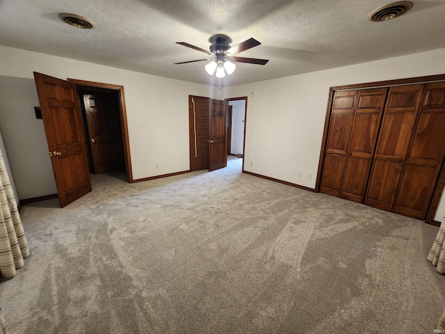 unfurnished bedroom with ceiling fan, light colored carpet, and a textured ceiling