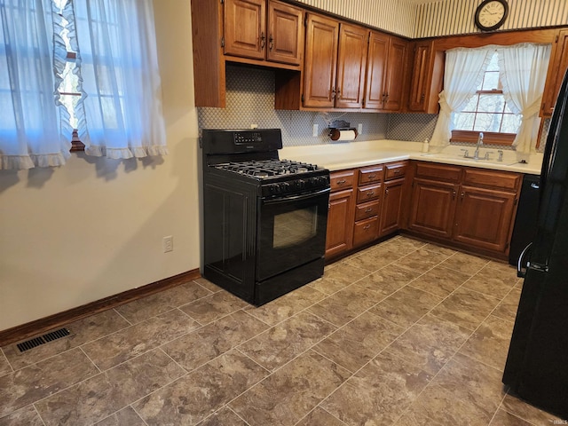 kitchen with tasteful backsplash, black range with gas cooktop, and sink