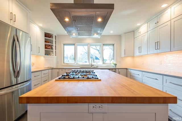 kitchen featuring stainless steel appliances, butcher block countertops, a kitchen island, and white cabinets