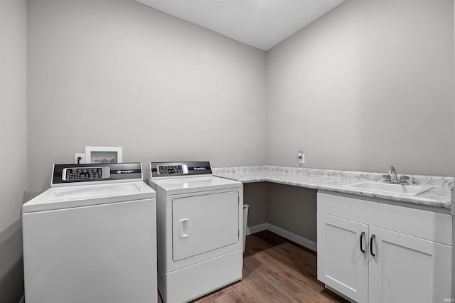 clothes washing area with sink, cabinets, washing machine and dryer, and dark hardwood / wood-style floors