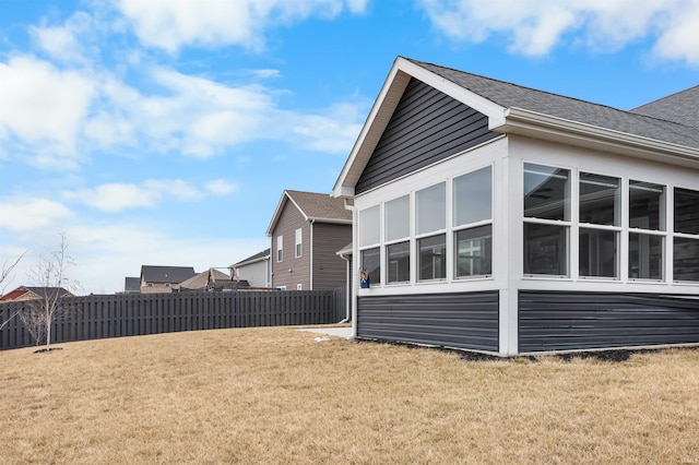 view of side of home with a sunroom and a yard