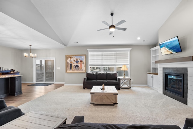 carpeted living room featuring ceiling fan with notable chandelier, plenty of natural light, a fireplace, and vaulted ceiling