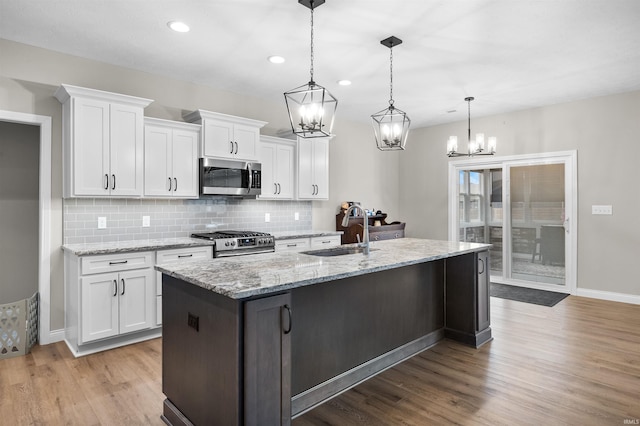 kitchen with pendant lighting, stainless steel appliances, sink, and white cabinets