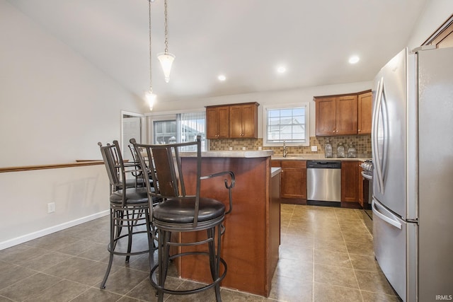 kitchen with a breakfast bar, decorative light fixtures, a kitchen island, stainless steel appliances, and backsplash