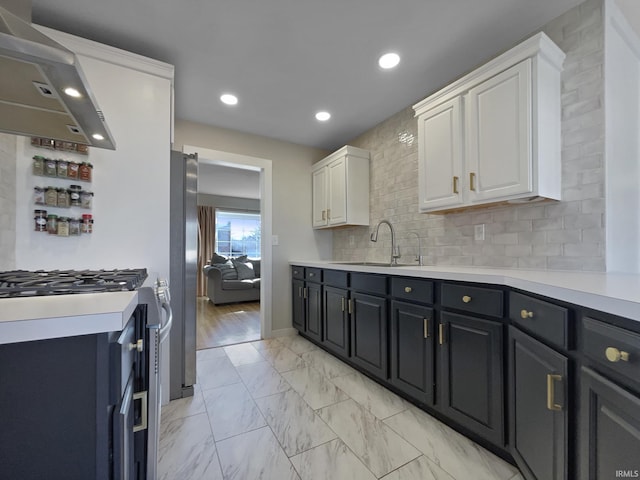 kitchen featuring sink, tasteful backsplash, stainless steel appliances, range hood, and white cabinets