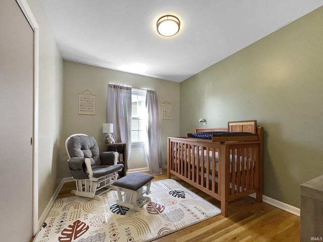 bedroom featuring a crib and light hardwood / wood-style flooring