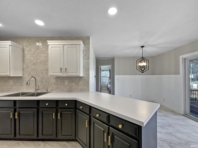 kitchen with white cabinetry, sink, decorative backsplash, and kitchen peninsula