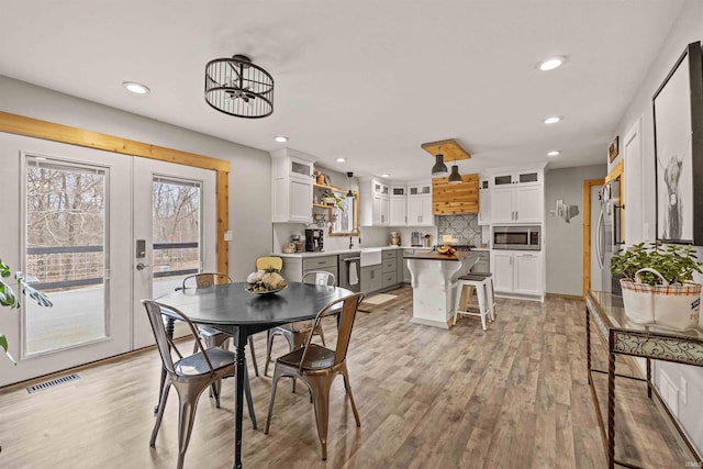 dining space with sink, light hardwood / wood-style floors, and french doors