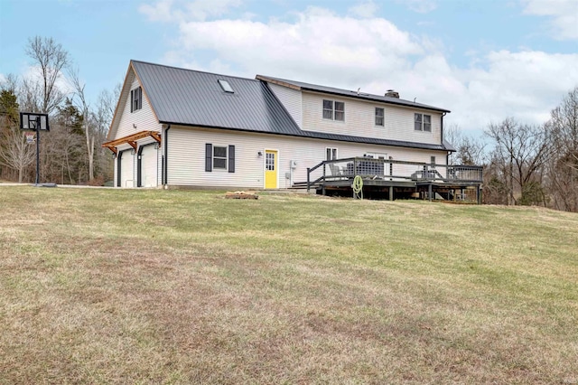 rear view of property featuring a garage, a deck, and a lawn