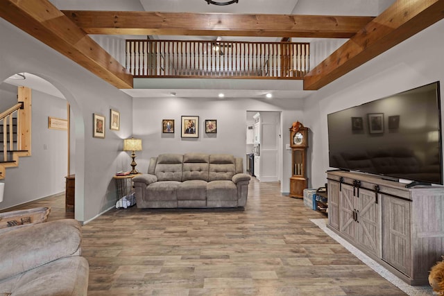 living room with a towering ceiling, wood-type flooring, and beamed ceiling