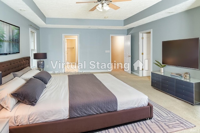 bedroom featuring light colored carpet, a raised ceiling, and a textured ceiling