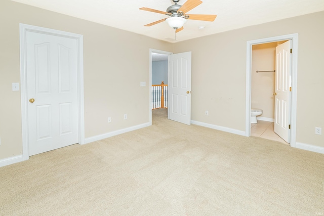 unfurnished bedroom featuring ceiling fan, light colored carpet, and ensuite bath