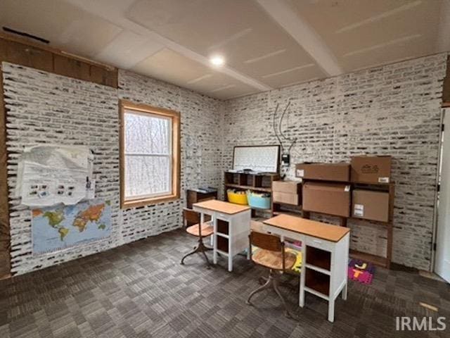 home office featuring dark carpet and brick wall