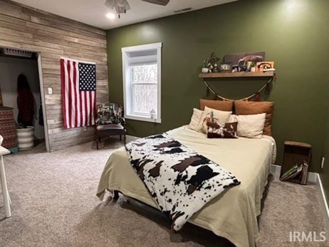 carpeted bedroom with wooden walls and ceiling fan