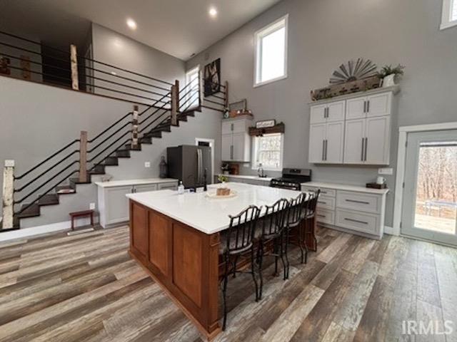 kitchen with appliances with stainless steel finishes, a center island, a healthy amount of sunlight, white cabinets, and dark hardwood / wood-style flooring