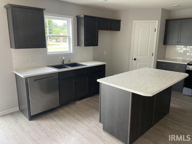 kitchen featuring sink, appliances with stainless steel finishes, tasteful backsplash, light hardwood / wood-style floors, and a kitchen island