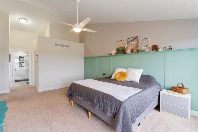 carpeted bedroom with ensuite bath, vaulted ceiling, and ceiling fan