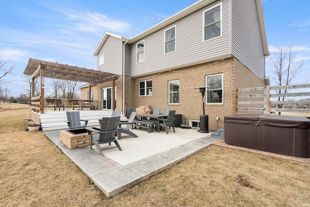 rear view of property featuring a yard, a hot tub, a pergola, and a patio area