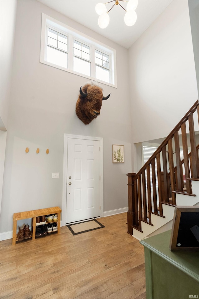 entrance foyer featuring an inviting chandelier, hardwood / wood-style flooring, and a high ceiling