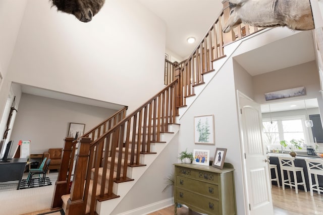 stairway with a towering ceiling and wood-type flooring