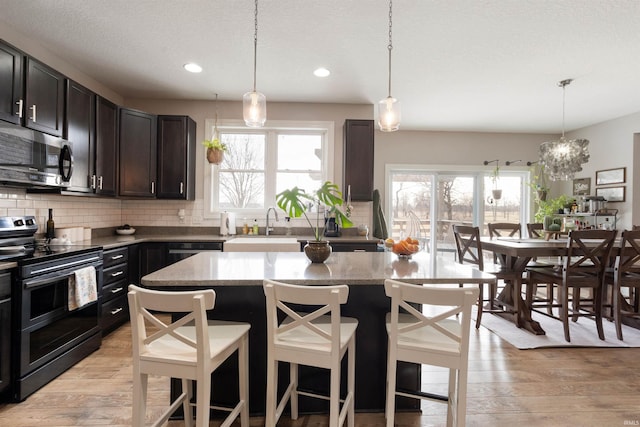 kitchen with stainless steel appliances, a kitchen island, sink, and pendant lighting