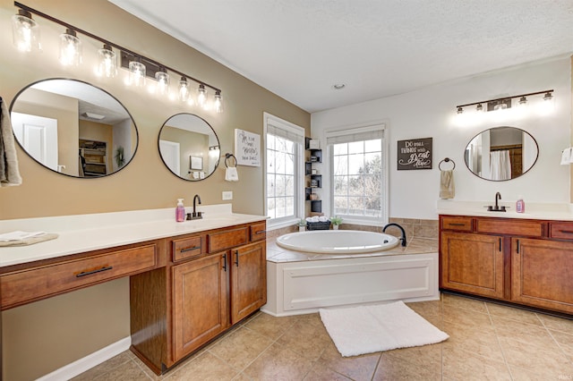 bathroom with a tub to relax in, vanity, tile patterned floors, and a textured ceiling