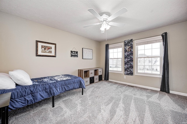 carpeted bedroom featuring ceiling fan and a textured ceiling