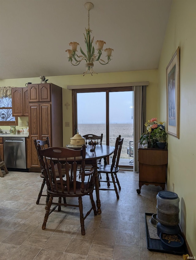 dining area featuring vaulted ceiling, a water view, and an inviting chandelier
