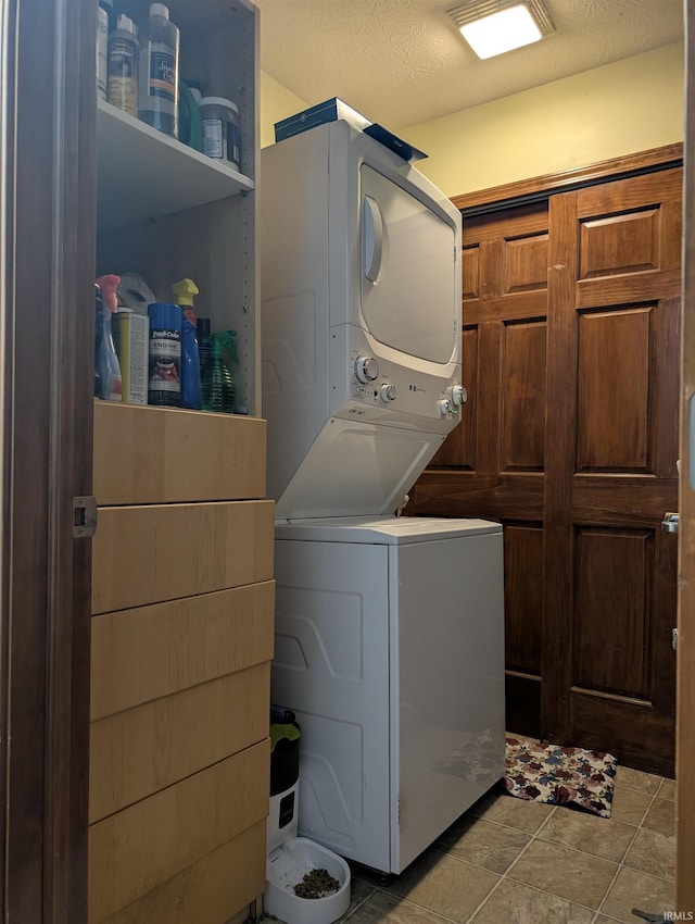 clothes washing area featuring a textured ceiling and stacked washer / dryer