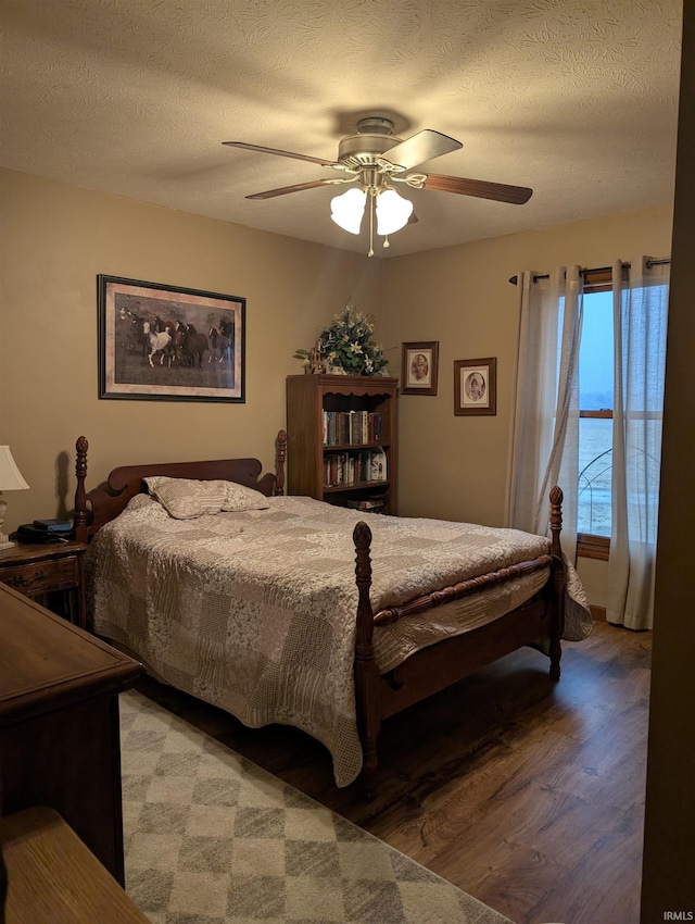 bedroom featuring ceiling fan, hardwood / wood-style floors, and a textured ceiling