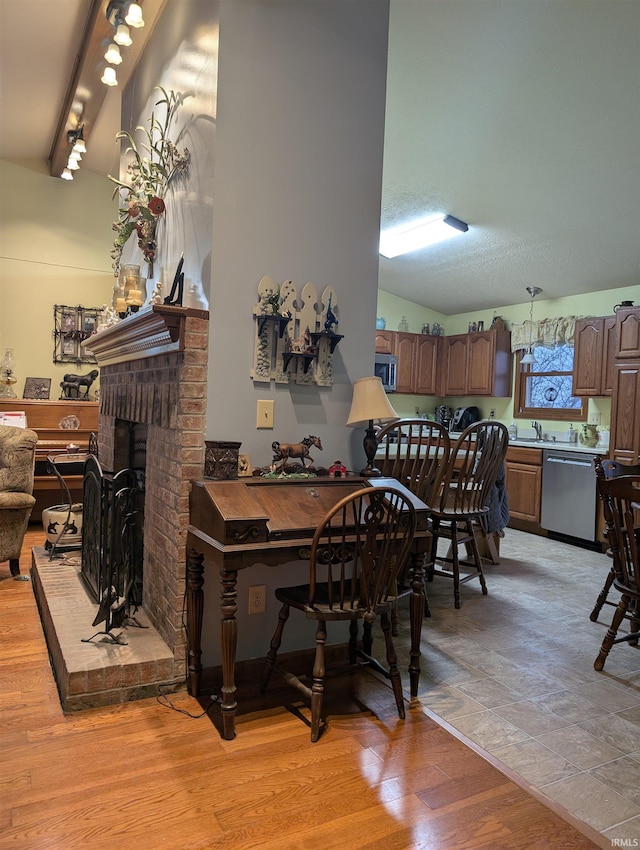 dining room featuring a fireplace, sink, beam ceiling, and light wood-type flooring