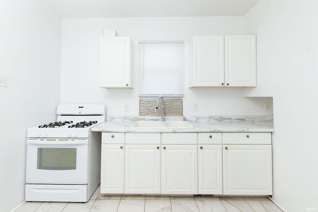 kitchen featuring white cabinetry, sink, light stone counters, and white gas range oven