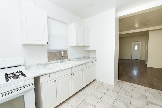 kitchen with sink, light stone countertops, white cabinets, and white gas stove