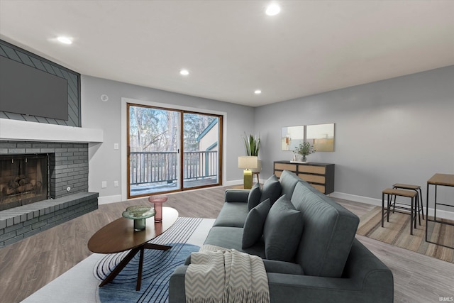 living room featuring a brick fireplace and light wood-type flooring