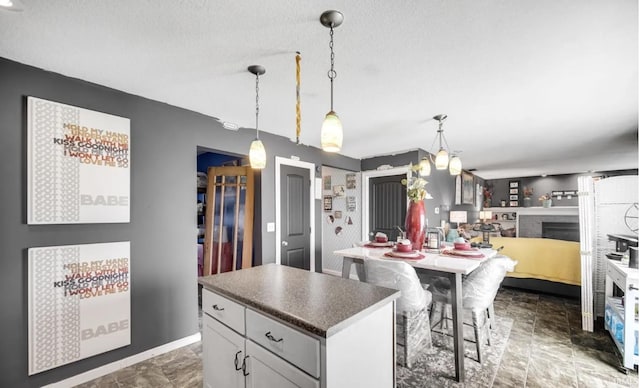 kitchen featuring a breakfast bar area, a center island, a brick fireplace, hanging light fixtures, and a textured ceiling