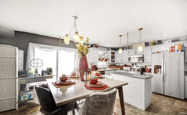 kitchen with stainless steel appliances, white cabinetry, hanging light fixtures, and a kitchen island