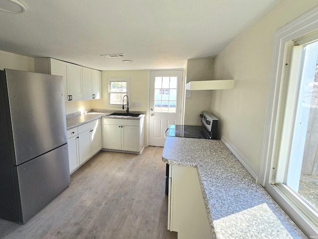 kitchen with white cabinetry, sink, light wood-type flooring, and appliances with stainless steel finishes