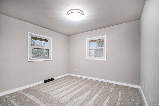 empty room with plenty of natural light and carpet flooring