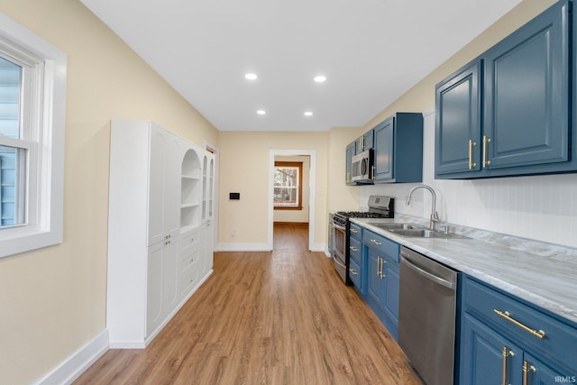 kitchen with stainless steel appliances, sink, blue cabinetry, and light wood-type flooring